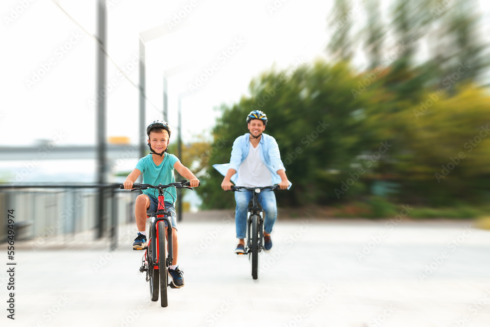 Dad and son riding bicycles together outdoors, motion blur effect Dad and son riding bicycles together outdoors, motion blur effect