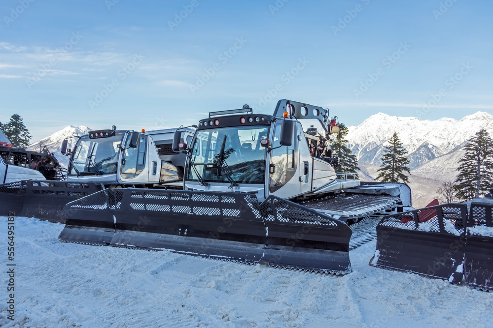 Parking on the slope of snowplows for the ski resort. Snow plow bulldozer ratrac runs around the slopes for skiing and snowboarding in the mountains. Parking on the slope of snowplows for the ski resort. Snow plow bulldozer ratrac runs around the slopes for skiing and snowboarding in the mountains.