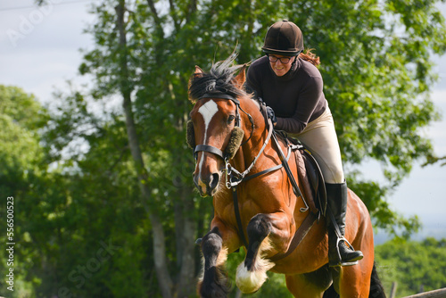Close up shot of smiling young female rider jumping in the English countryside enjoying the excitement of risk.