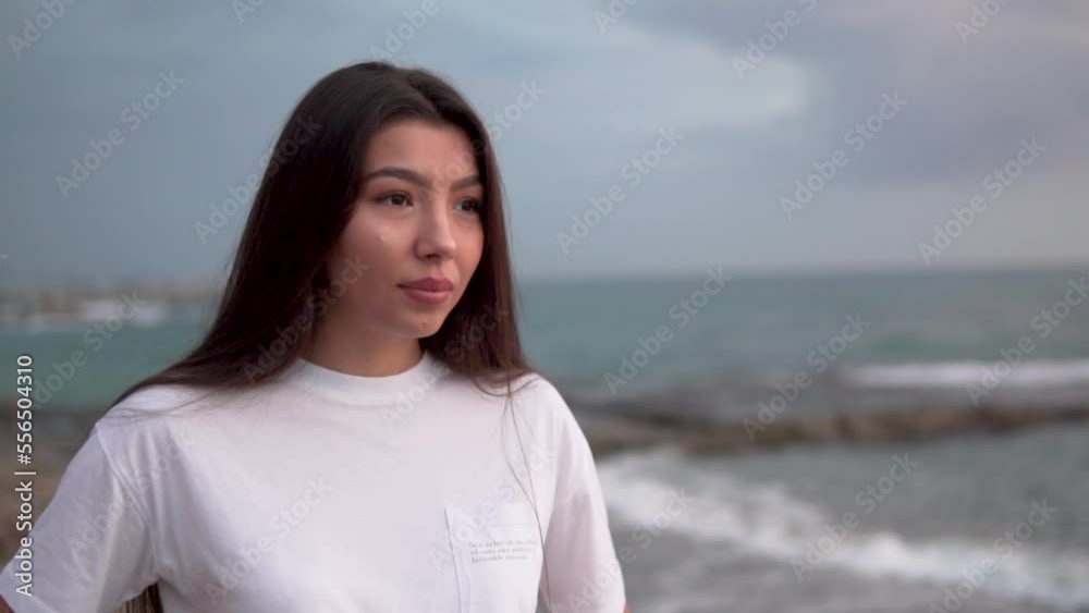 A beautiful young woman of Asian appearance against the background of an overcast sky and sea. A beautiful young woman of Asian appearance against the background of an overcast sky and sea.