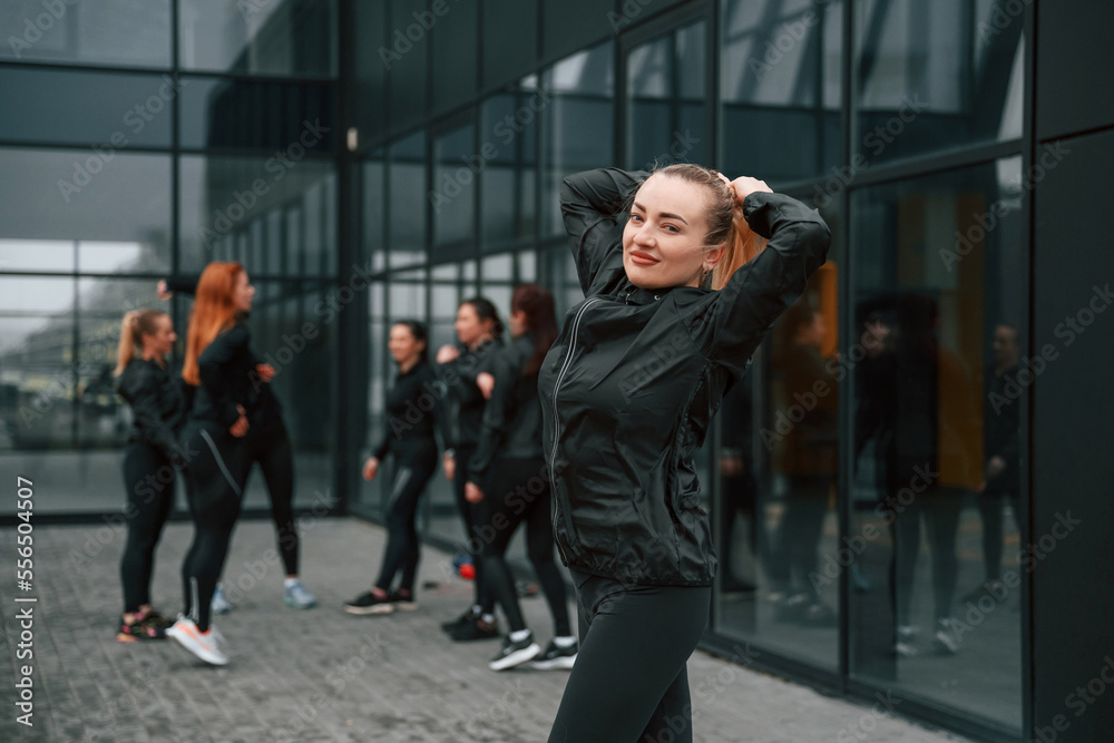 Obraz premium Group of sportive women is outdoors near black building