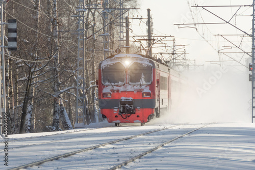 Express obsolete electric train rushes lifting snow into the air winter landscape.