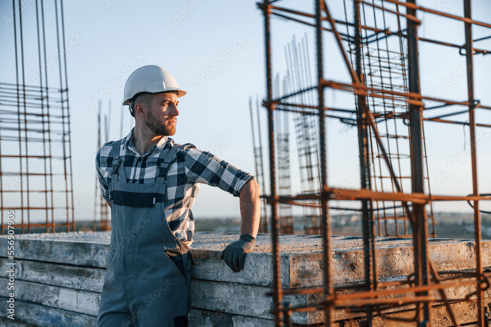 Standing and taking a break. Man is working on the construction site at daytime Standing and taking a break. Man is working on the construction site at daytime