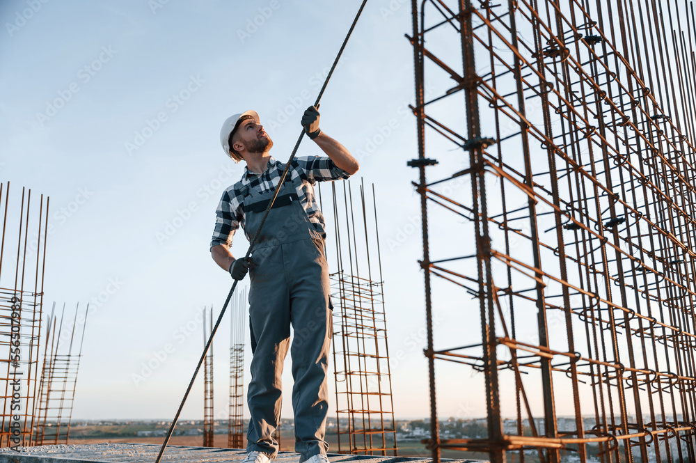 Holding metal object in hands. Man is working on the construction site at daytime Holding metal object in hands. Man is working on the construction site at daytime