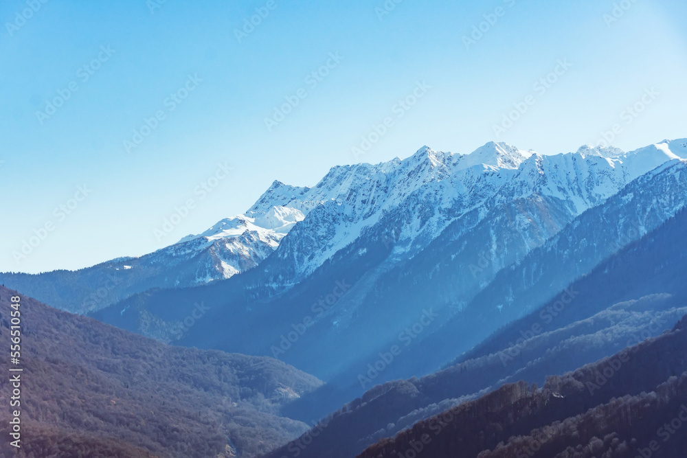 Mountain snowy landscape forest, mountain range pass blue sky. The gorge between the ridges.