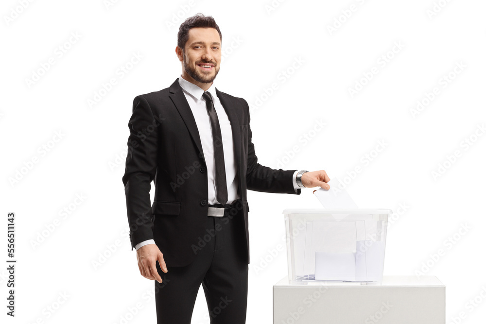Professional man in a suit casting a vote in a ballot box and looking at the camera Professional man in a suit casting a vote in a ballot box and looking at the camera