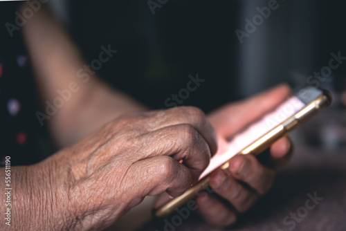 Hands of an elderly woman holding a mobile phone.
