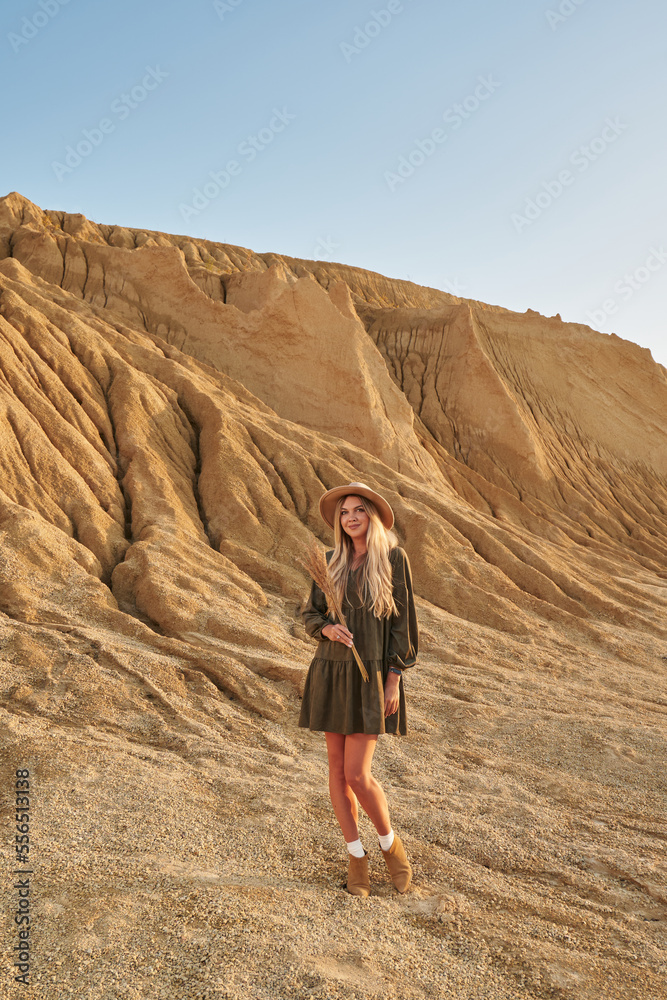 high sand mountain, beautiful natural landscape. beautiful young woman with a bouquet of grass in a hat and dress in a natural shade