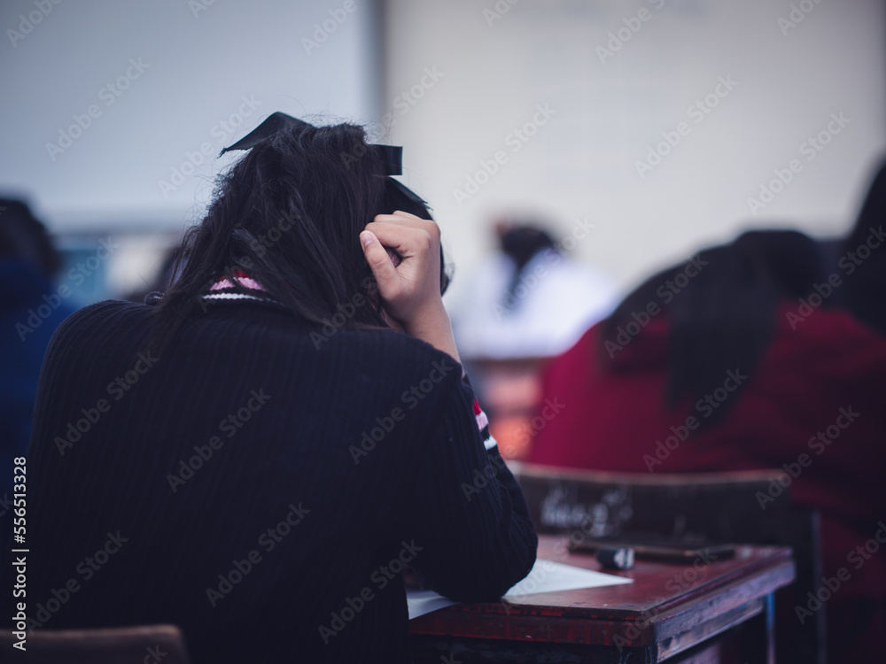 University students reading exam answer sheets exercises in classroom of school with headache.and stress.