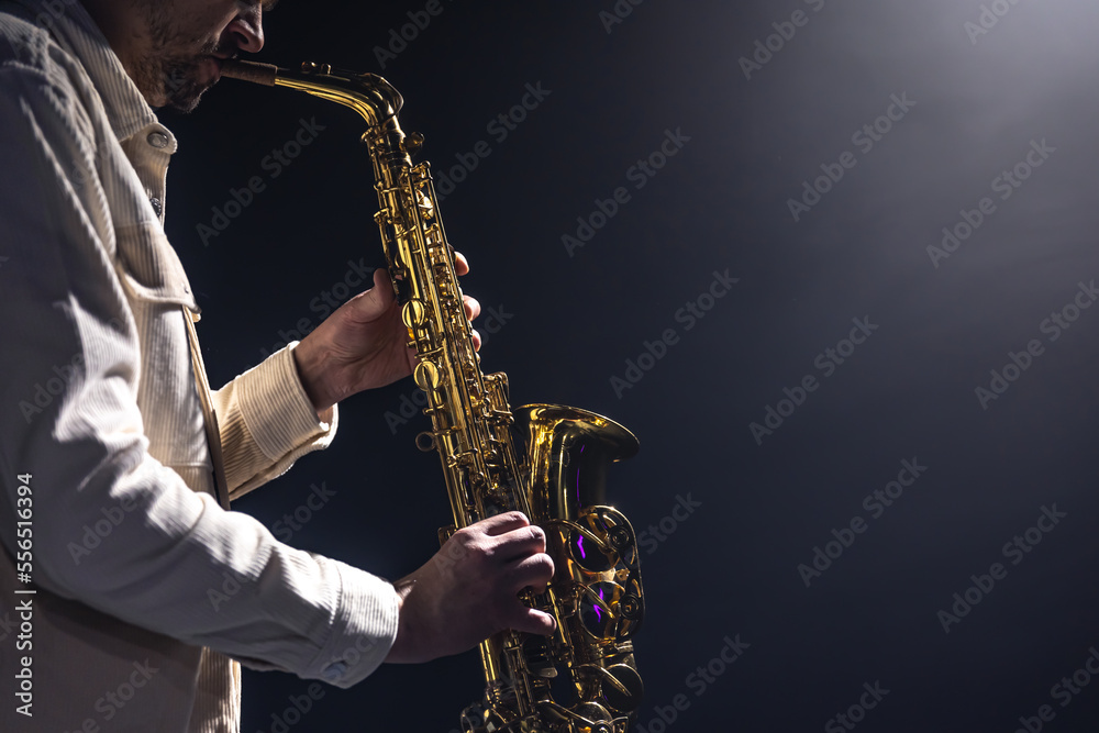 Obraz premium A European man plays the saxophone in the dark.