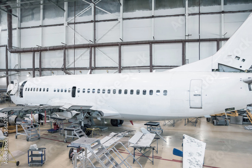 White passenger airliner in the hangar. Jetliner under maintenance. Checking mechanical systems for flight operations