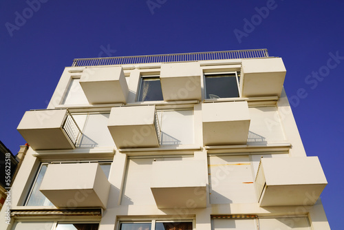 new modern white facade building with square balcony and cube terrace in blue sky photo