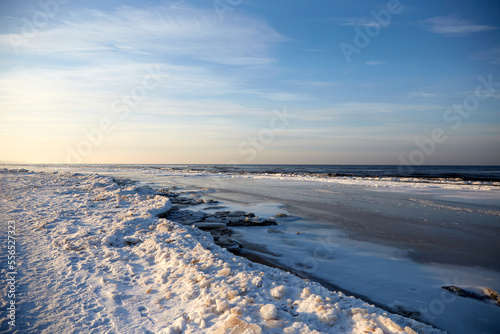 Winter landscape with icy sea coast and calm blue sky  selective focus