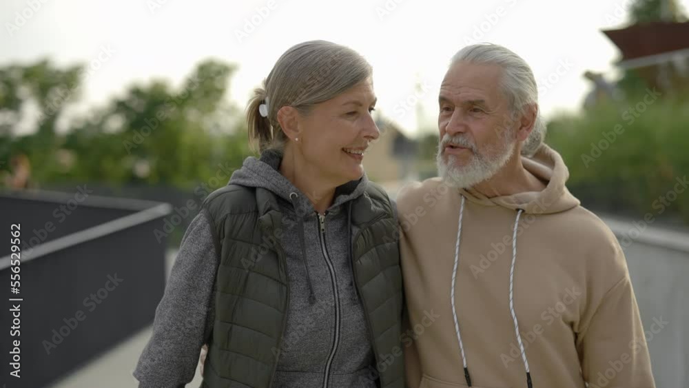 Mature happy couple walking together in the park, talking, laughing. Elderly family feeling in love. Happy pensioners. People, love and relationship concept. Mature happy couple walking together in the park, talking, laughing. Elderly family feeling in love. Happy pensioners. People, love and relationship concept.