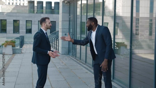 Angry man boss scolding an employee for a bad job while standing near the office building. The tyrant boss yells at his subordinate and insults him, showing personal contempt. Conflict at work concept