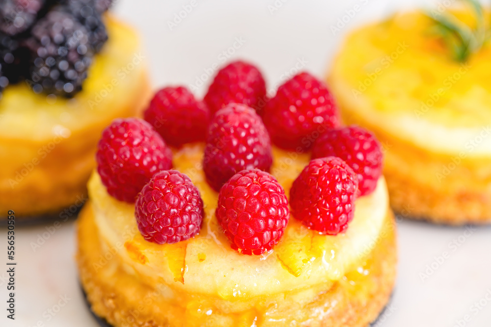 Cheesecakes with berries and orange jelly close-up. Mini cheesecakes with different types of toppings Cheesecakes with berries and orange jelly close-up. Mini cheesecakes with different types of toppings