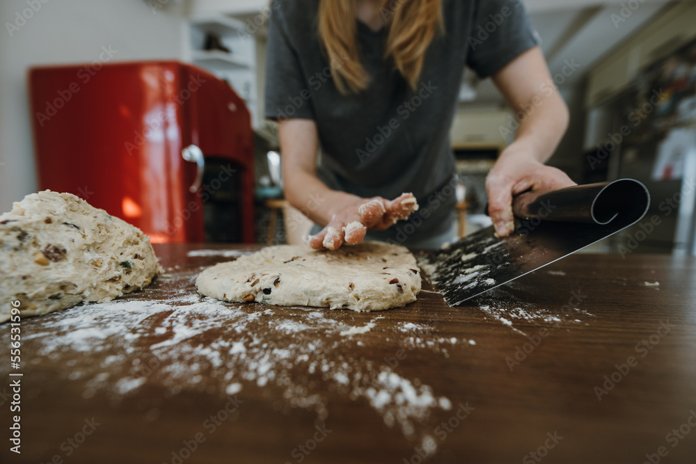 Fototapeta premium Female hands preparing dough for stollen with scraper.