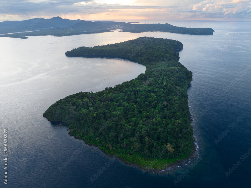 Dawn illuminates a remote tropical island fringed by a coral reef in