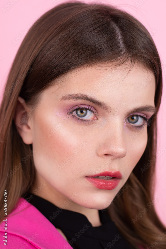 Obraz premium A girl with beautiful blue bright eyes with make up, pink lipstick eyebrows. Fashion, beauty, makeup, cosmetics, beauty salon,style. Vertical frame Pink background