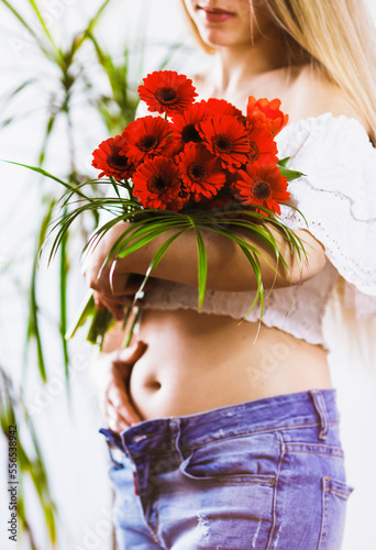 Close-up of a woman at first month of pregnancy. The blurry girl and flowers in focus