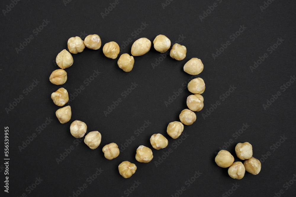 on a dark background, a heart made of hazelnut kernels is laid out. concept of love for nuts. healthy and useful food. on a dark background, a heart made of hazelnut kernels is laid out. concept of love for nuts. healthy and useful food.