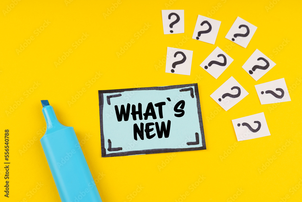 On the yellow surface is a marker, question marks and a sticker with the inscription - What s New On the yellow surface is a marker, question marks and a sticker with the inscription - What s New