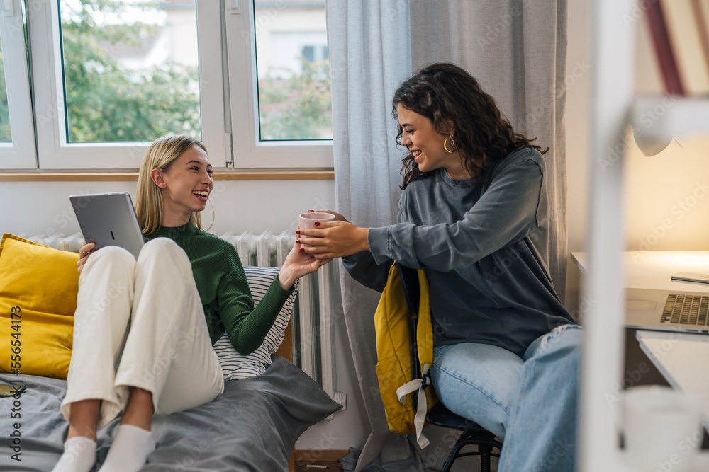 Obraz premium College student is passing a coffee cup to her friend