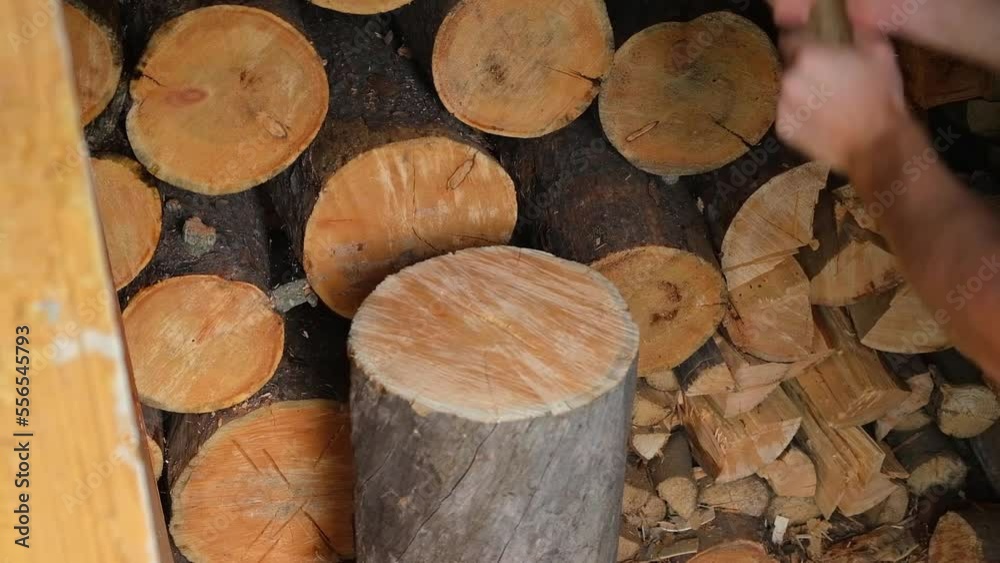 A man is chopping logs with an axe on chopping block. Harvesting of firewood stocks for heating. An alternative source of thermal energy instead of natural gas. A man is chopping logs with an axe on chopping block. Harvesting of firewood stocks for heating. An alternative source of thermal energy instead of natural gas.