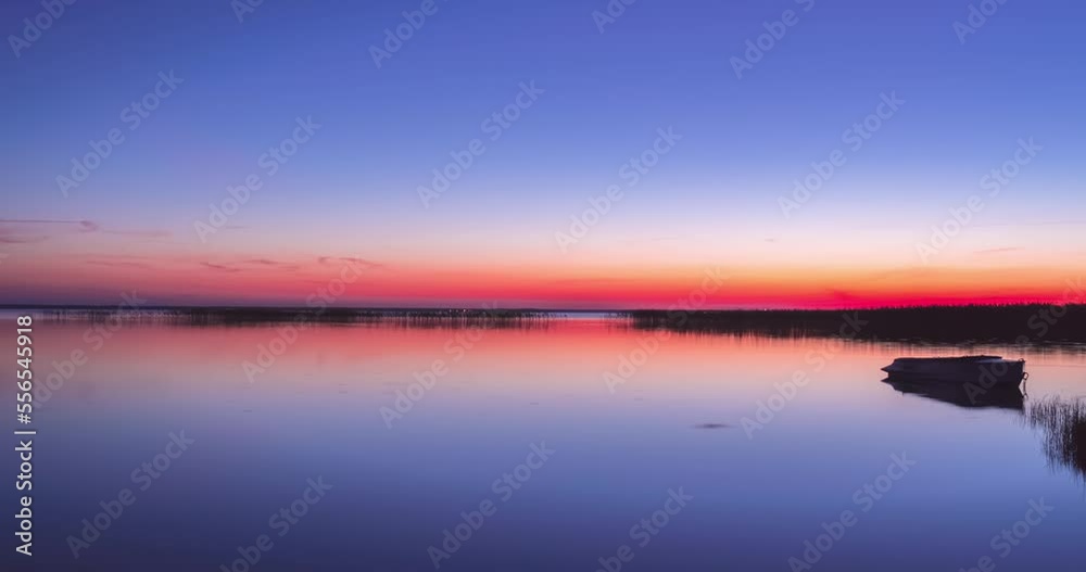 Beautiful sunrise on flat lake with boat. Timelapse, time is accelerated