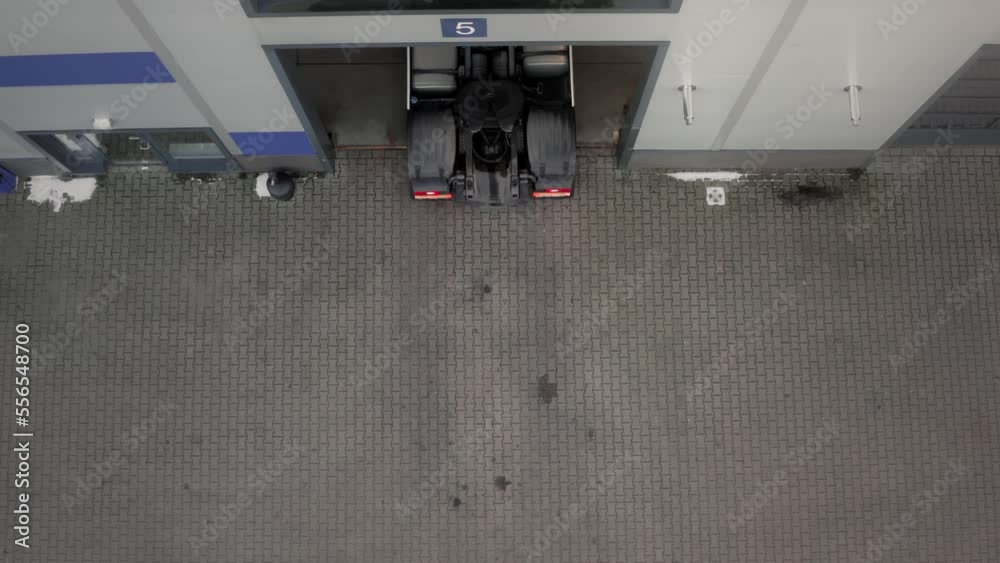 The truck tractor for international cargo transportation slowly drives out of the open garage gate in reverse. Transport and logistics, TIR.