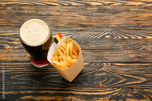 Glass of Belgium beer and french fries on wooden background photo