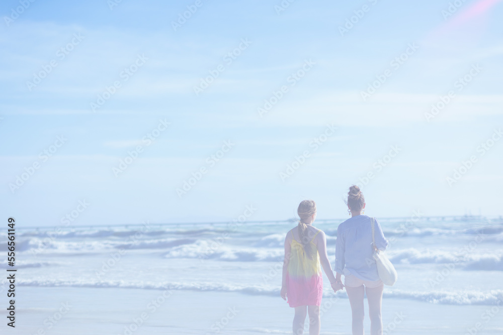 Seen from behind stylish mother and teenage daughter at beach Seen from behind stylish mother and teenage daughter at beach