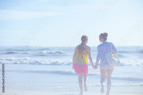 Seen from behind modern mother and child at beach running