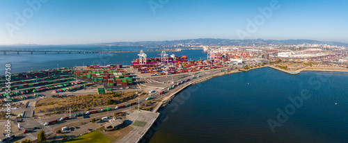 The Oakland Outer Harbor aerial view. Loaded trucks moving by Container cranes. View of busy Port of Oakland. Shipping terminal facility.