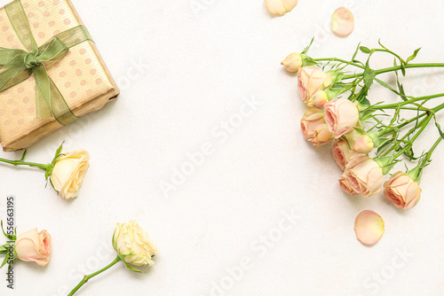 Composition with beautiful rose flowers and gift box on light background