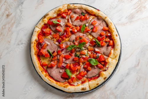 Italian meat pizza with roastbeef, tomatoes, basil and red onion on marble table top view