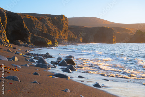 Scenic Beach with Black Sand by Low Tide at Sunset near Kopasker village, Volcanic coastline in Iceland photo