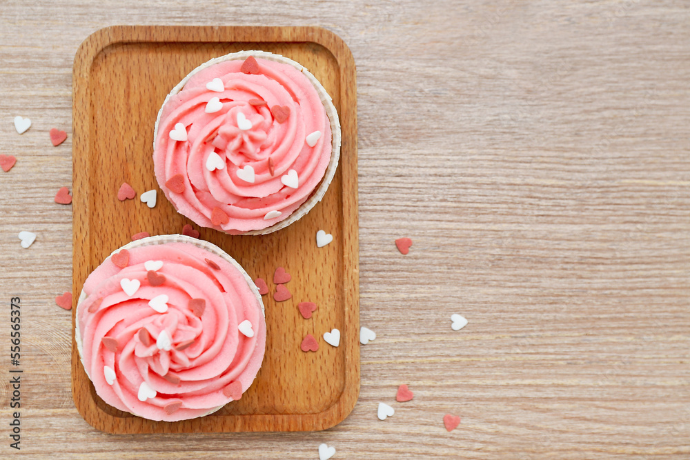 Board with tasty cupcakes and hearts for Valentine's Day on wooden background Board with tasty cupcakes and hearts for Valentine's Day on wooden background