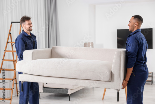 Male movers carrying sofa in new house