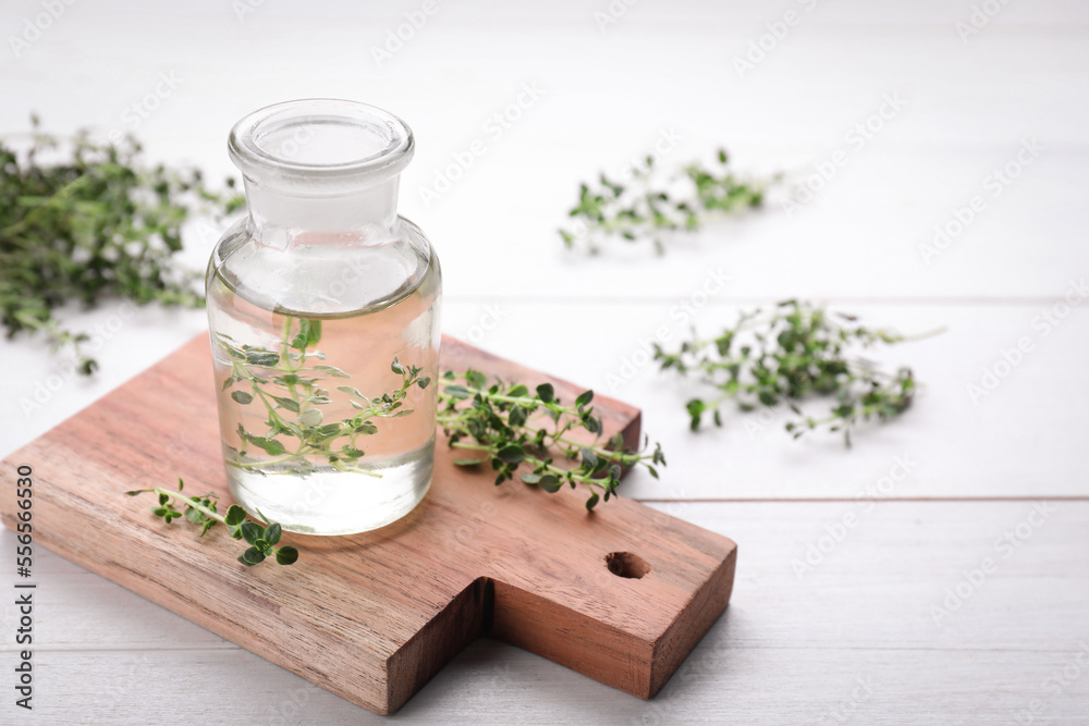 Bottle of thyme essential oil and fresh plant on white wooden table, space for text Bottle of thyme essential oil and fresh plant on white wooden table, space for text