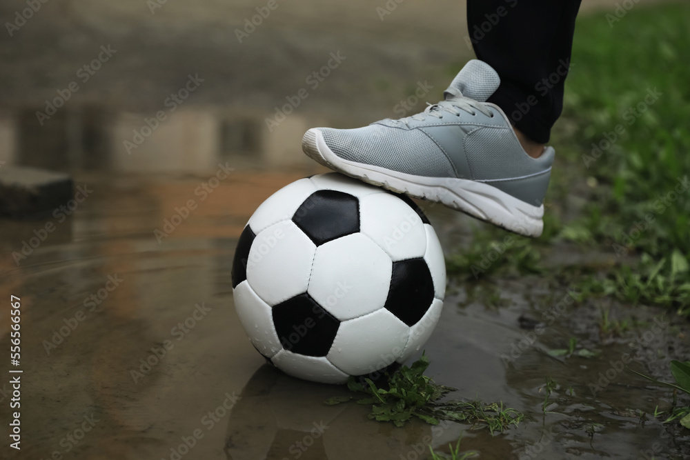 Man with soccer ball in puddle outdoors, closeup