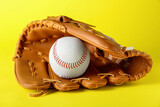 Catcher's mitt and baseball ball on yellow background. Sports game