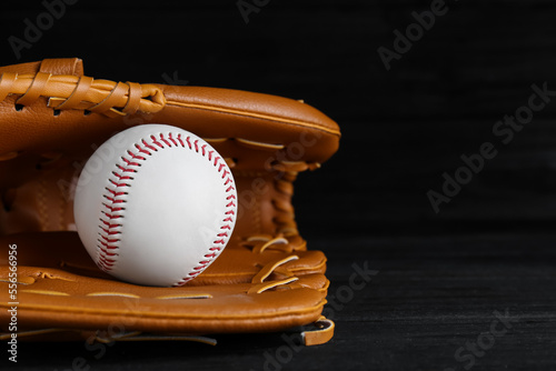 Catcher's mitt and baseball ball on black background, space for text. Sports game