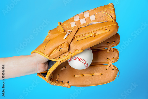 Photography Baseball player holding ball with catcher's mitt on light blue background, closeup