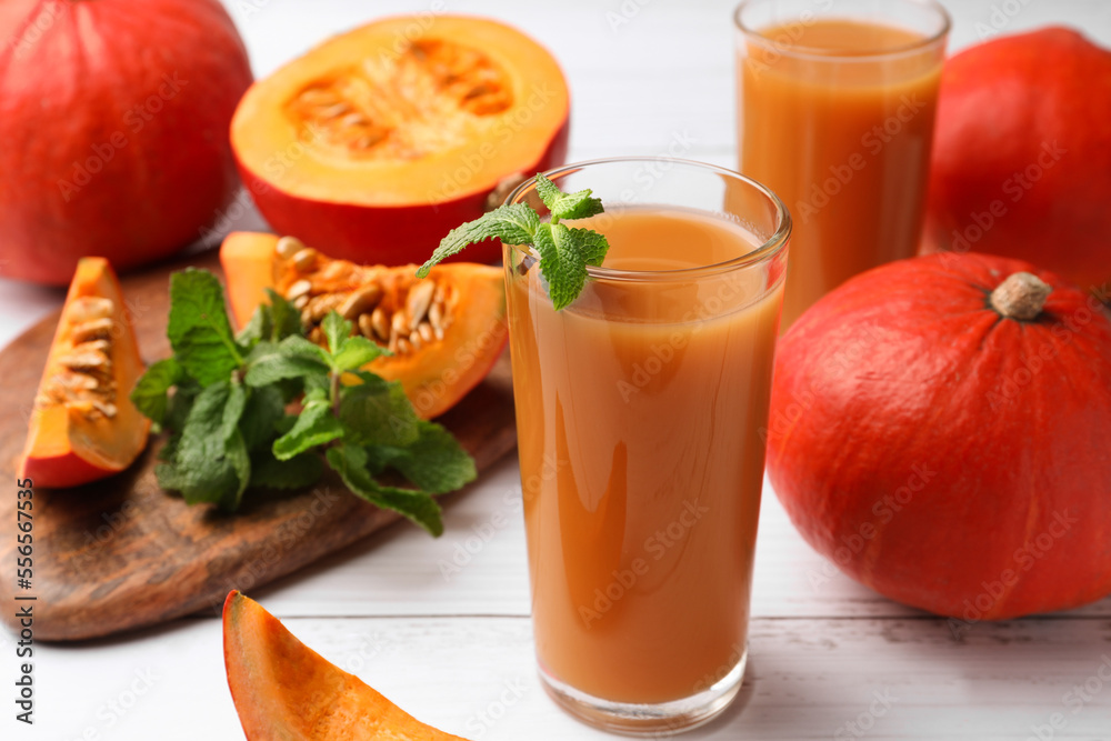 Tasty pumpkin juice and pumpkins on white wooden table Tasty pumpkin juice and pumpkins on white wooden table