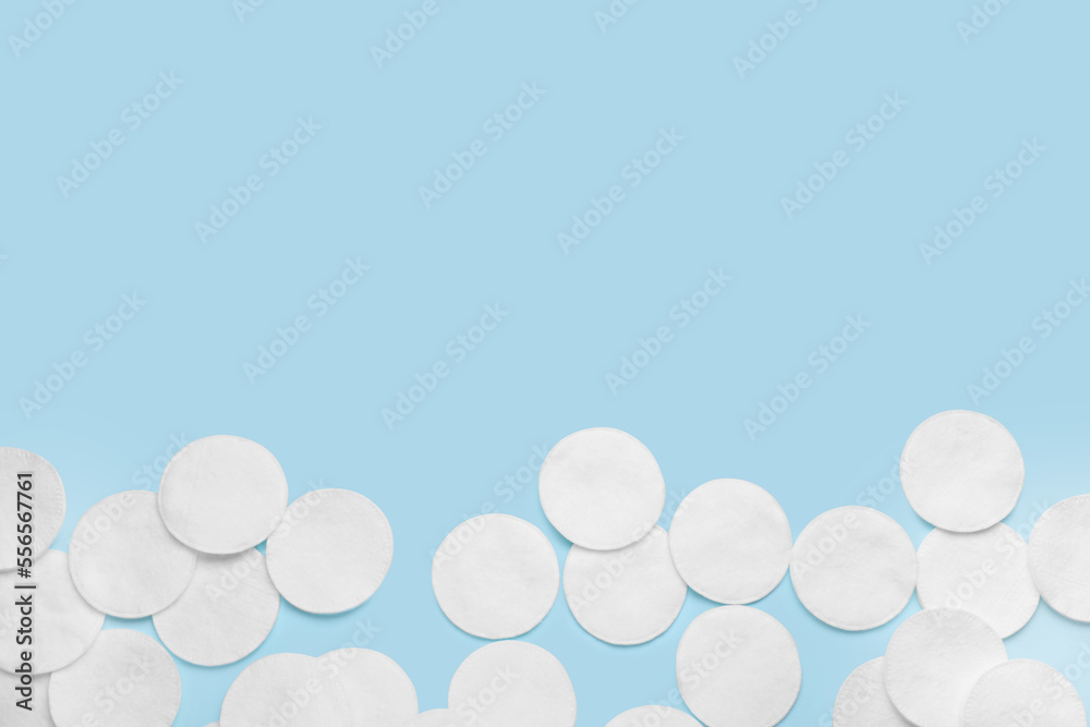 Many cotton pads on light blue background, flat lay. Space for text Many cotton pads on light blue background, flat lay. Space for text