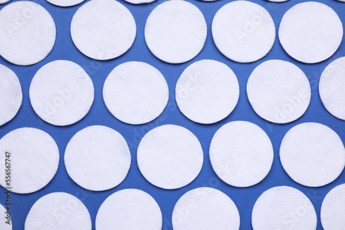Many cotton pads on blue background, flat lay