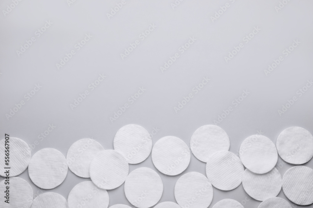 Many clean cotton pads on light grey background, flat lay. Space for text