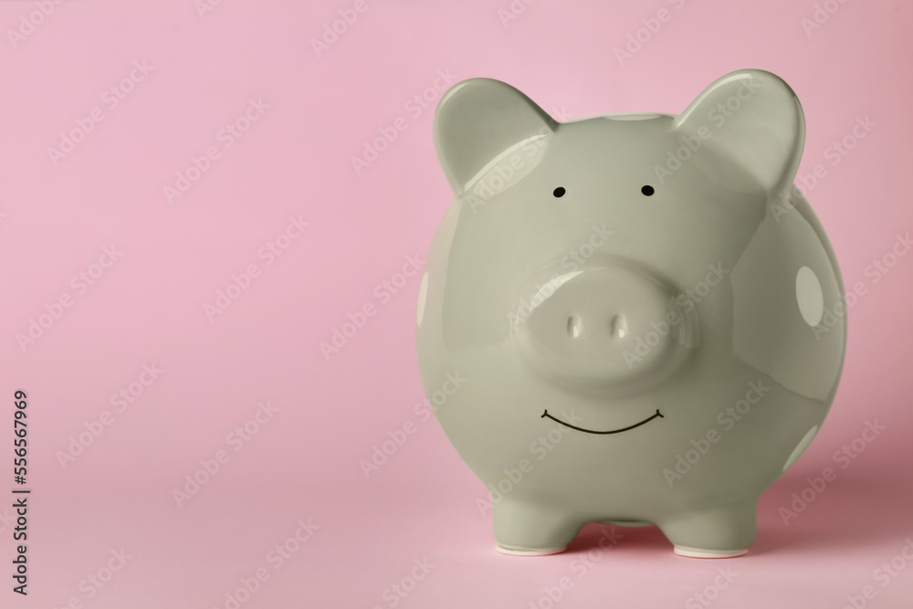 Ceramic piggy bank on pink background. Space for text