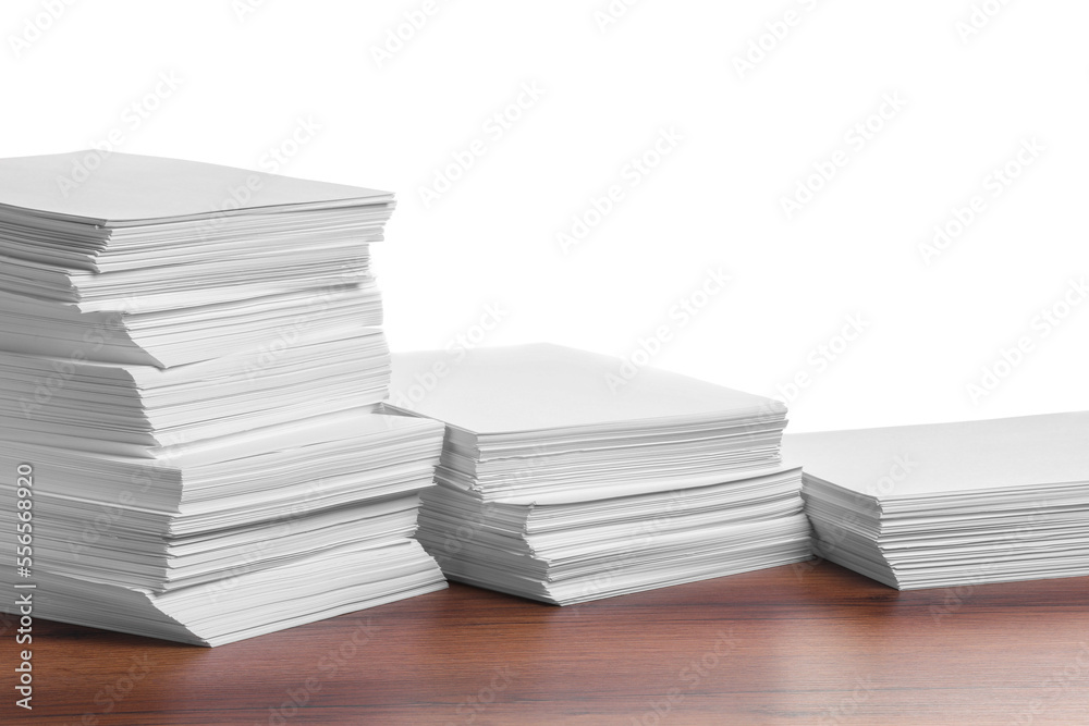 Stacks of paper sheets on wooden table against white background Stacks of paper sheets on wooden table against white background